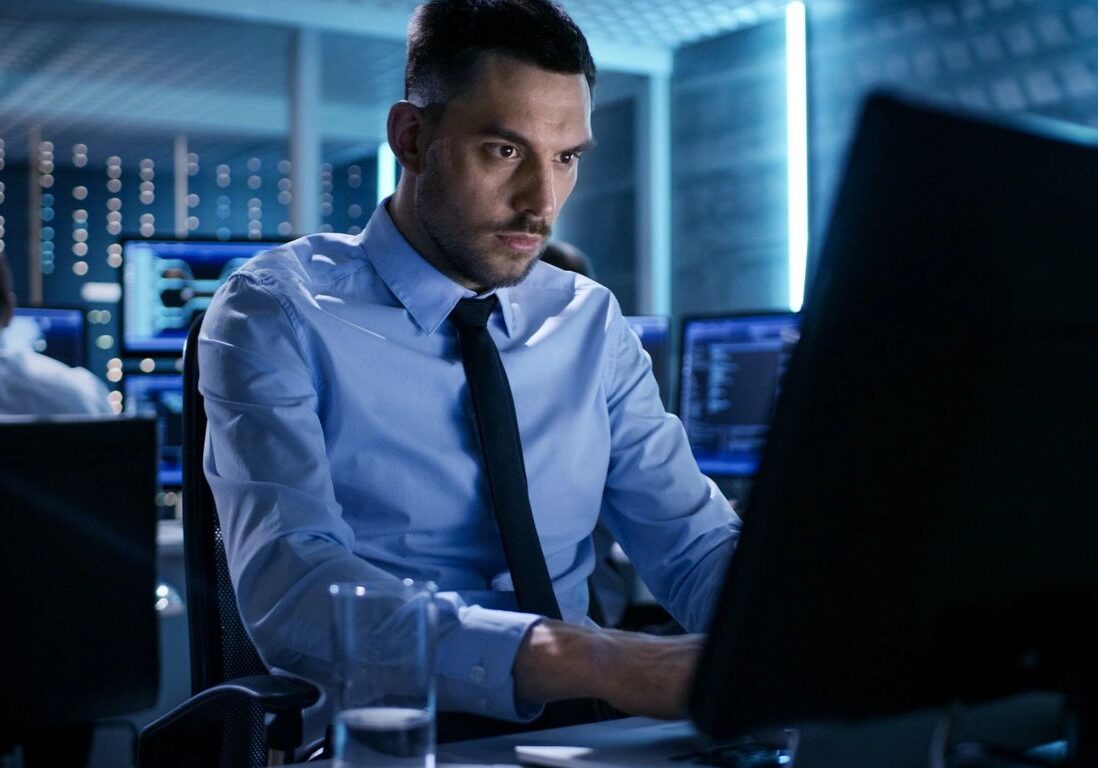 Focused man in business attire working on a computer in an office.